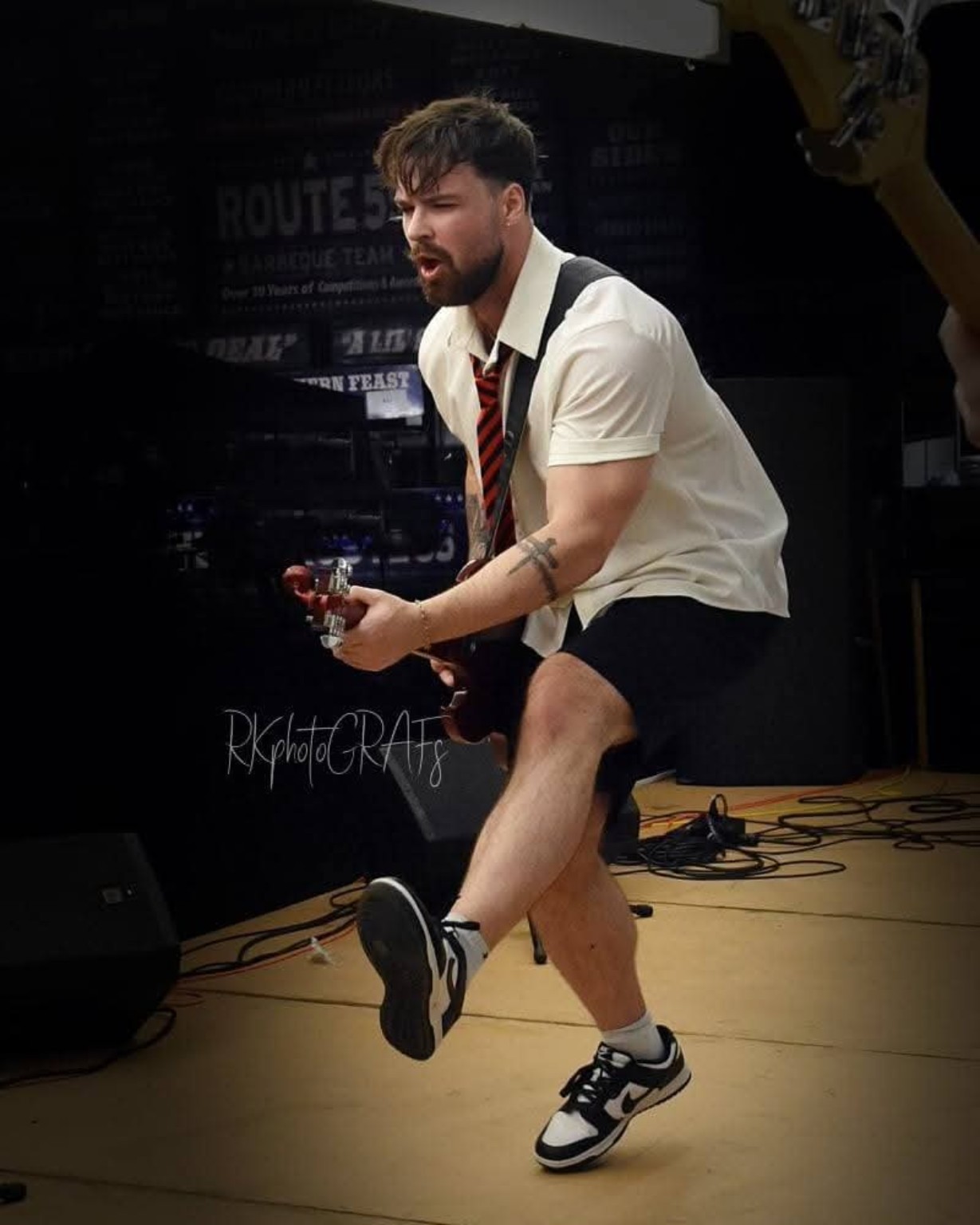 AC/DC ERAS guitarist kicking forward during a performance