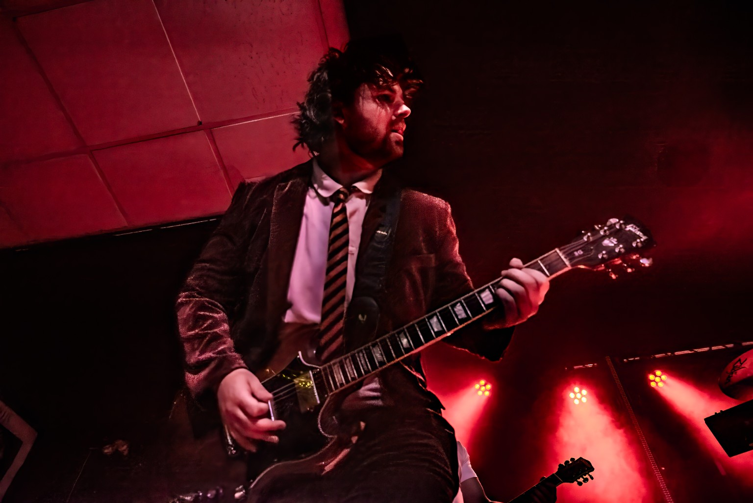 AC/DC ERAS guitarist performing under red stage lights